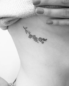 a woman's stomach with a small flower tattoo on her left side ribcage