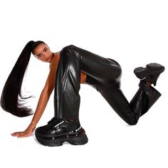 a woman in black leather pants and high heels posing for the camera with her legs spread out