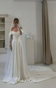 a woman in a wedding dress taking a selfie with her cell phone while wearing a veil