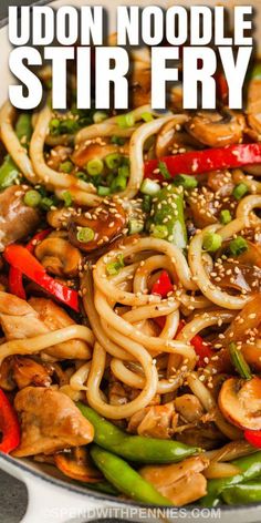 udon noodle stir fry in a pan with sesame seeds and green peppers on the side