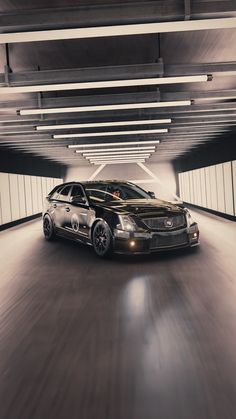 two cars are driving in an underground parking garage with their lights on and one is black