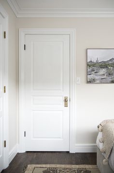 a white door in the corner of a room with a rug on the floor next to it