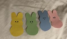 four different colored paper bunnies with faces drawn on them