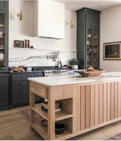 a large kitchen island in the middle of a room with wooden floors and green cabinets