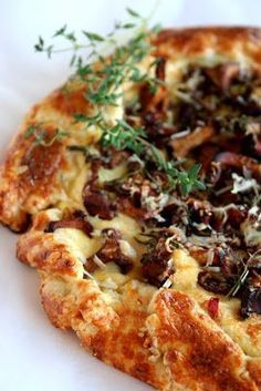 a close up of a pizza with toppings on a white table cloth and green garnish