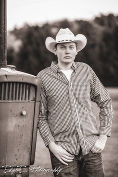 a man in a cowboy hat standing next to an old fashioned gas pump with his hands on his hips