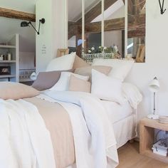 a bed with white linens and pillows in a bedroom next to a wooden floor