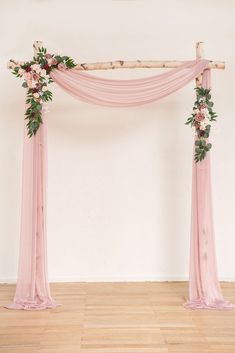 a wedding arch decorated with pink flowers and greenery