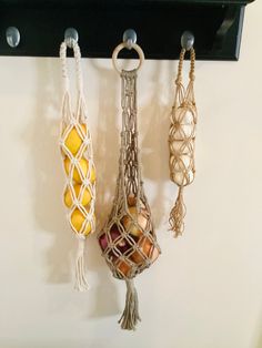 three macrame hangings on a wall next to each other with fruit in them