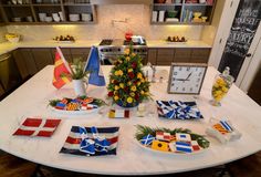 a table with plates and flags on it in the middle of a kitchen, next to a clock