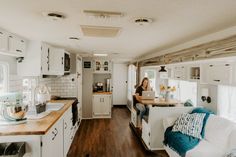 a kitchen and living room in a mobile home with wood flooring, white cabinets and counter tops