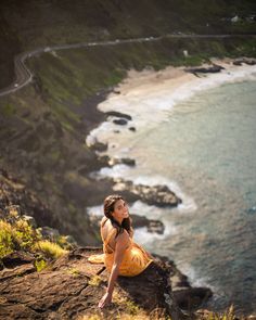 a woman sitting on top of a cliff next to the ocean