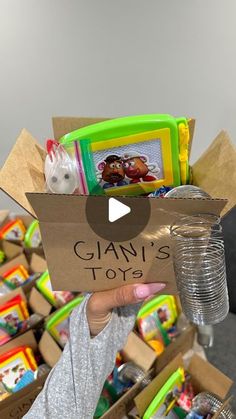 a person holding up a cardboard box with toys in it and the words giani's toys written on it