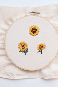 two yellow sunflowers on a white background are embroidered onto the back of an embroidery hoop