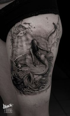 a woman's thigh with a mermaid tattoo on it