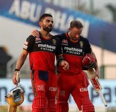 two men standing next to each other in red and black uniforms, one holding a bat