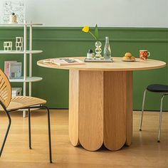 two chairs and a table in a room with green walls, wood flooring and bookshelves