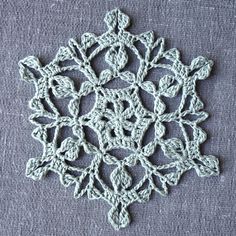 a crocheted snowflake is shown on a blue surface with white thread