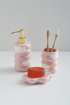 pink and white bathroom accessories with toothbrushes, soap or lotion dispenser