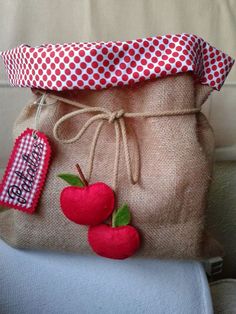 a bag with two cherries on it sitting on the back of a chair next to a pillow