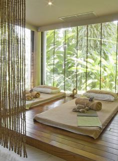 there are two beds in the room with wooden flooring and bamboo blinds on the windows