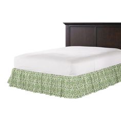 a bed with a green and white bedspread next to a wooden headboard