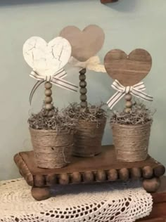 two small pots with hearts on them sitting on a wooden stand in front of a wall