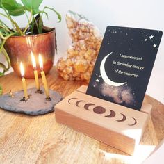 a wooden card holder with three candles on it and a quote about the phases of the moon