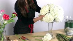 a woman arranging flowers in a vase on a table