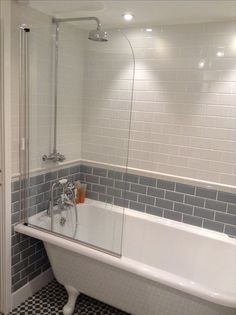 a bath tub sitting next to a white toilet in a bathroom with black and white tiles