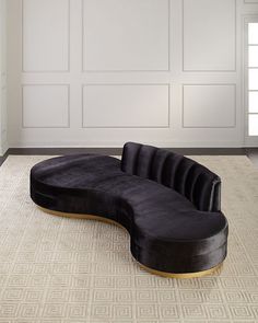 a black couch sitting on top of a rug in front of a white wall and door