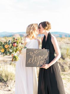 two women kissing each other in front of a sign that says we eloped