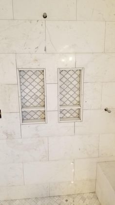 a white tiled bathroom with two open windows