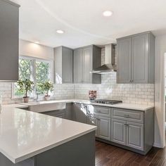 a kitchen with gray cabinets and white counter tops