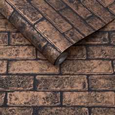 an old brick wall with a roll of brown paper on the ground next to it