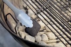 a bbq grill with rocks and a spatula on it's side,