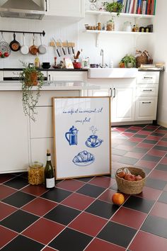 a kitchen with red and black tile flooring next to a basket of oranges