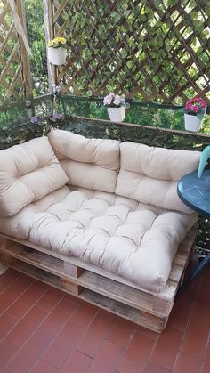 a couch made out of wooden pallets sitting on top of a brick floor next to a table