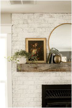 a white brick fireplace with a mirror and potted plants on top of the mantel