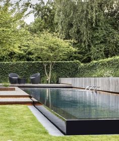 an outdoor swimming pool surrounded by grass and trees