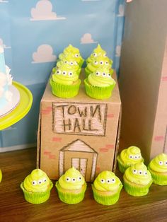 cupcakes with green frosting sitting in front of a cardboard box that says town hall