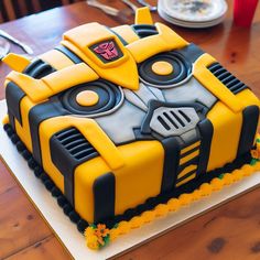 a birthday cake with a yellow and black robot design on the top is sitting on a wooden table