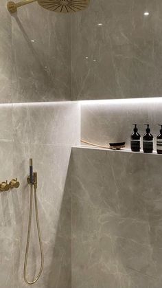 a bathroom with a shower head, shelves and soap dispensers