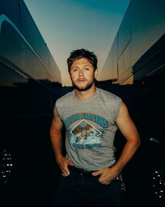 a man standing with his hands on his hips in front of a building at sunset