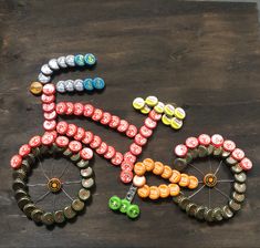 a bicycle made out of bottle caps sitting on top of a wooden table