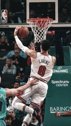 the basketball player is going to dunk the ball in front of the other player