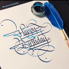 someone is writing happy birthday on a piece of paper with a blue pen and ink