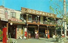 an old postcard shows people standing in front of a dogpatch store on the street