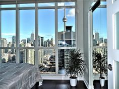 a bedroom with large windows and a view of the city from it's bed