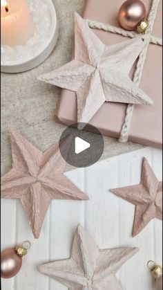 three star ornaments sitting on top of a table next to a candle and other decorations